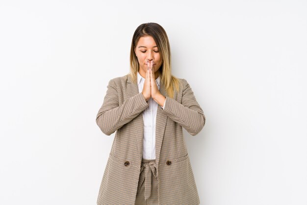 Young caucasian business woman holding hands in pray near mouth, feels confident.