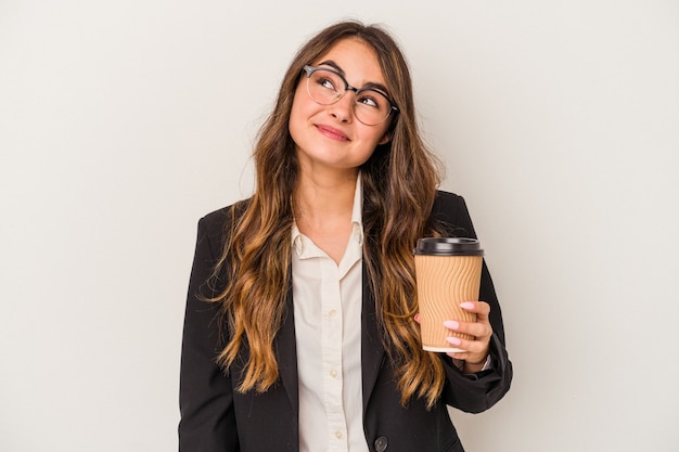 Young caucasian business woman holding a takeaway coffee isolated on white background dreaming of achieving goals and purposes