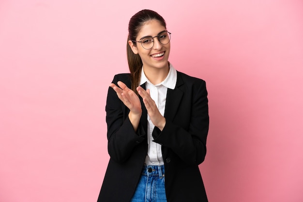 Young caucasian business woman isolated on pink background applauding after presentation in a conference