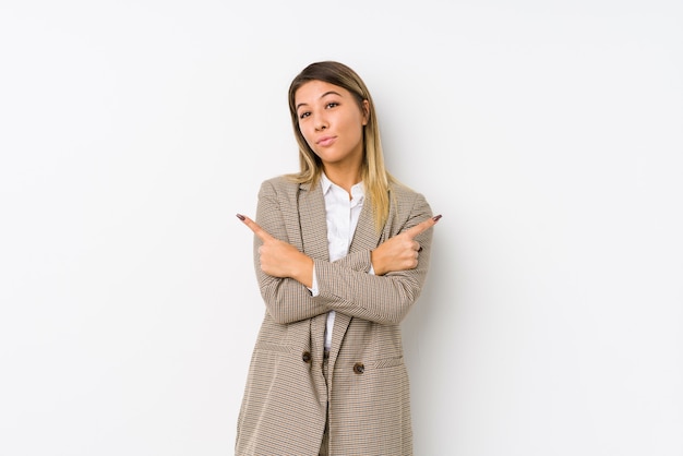 Young caucasian business woman isolated points sideways, is trying to choose between two options.