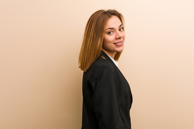 Young caucasian business woman looks aside smiling, cheerful and pleasant.