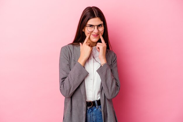 Young caucasian business woman on pink doubting between two options.