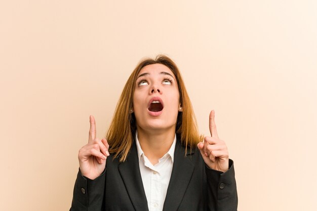 口を開けて逆さまを指している若い白人ビジネスウーマン。
