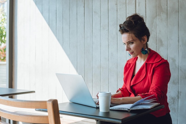 Young caucasian business woman using laptop looking at screen working in coffee shop