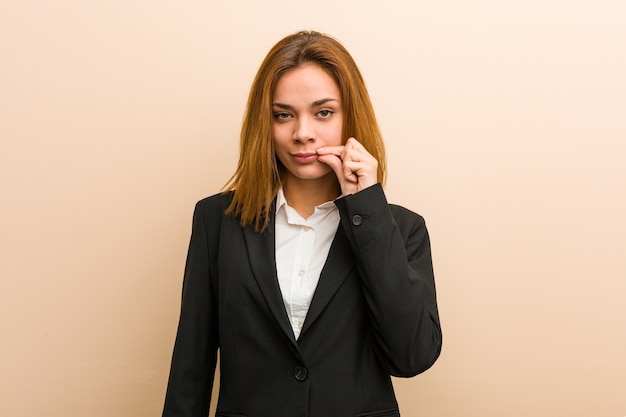 Young caucasian business woman with fingers on lips keeping a secret.