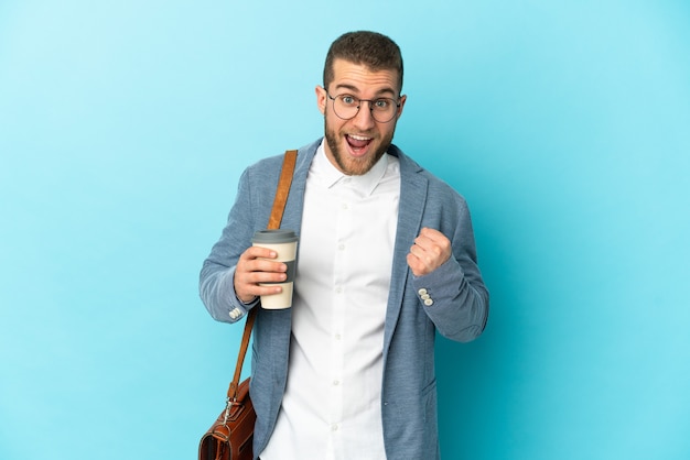 Young caucasian businessman isolated on blue celebrating a victory in winner position