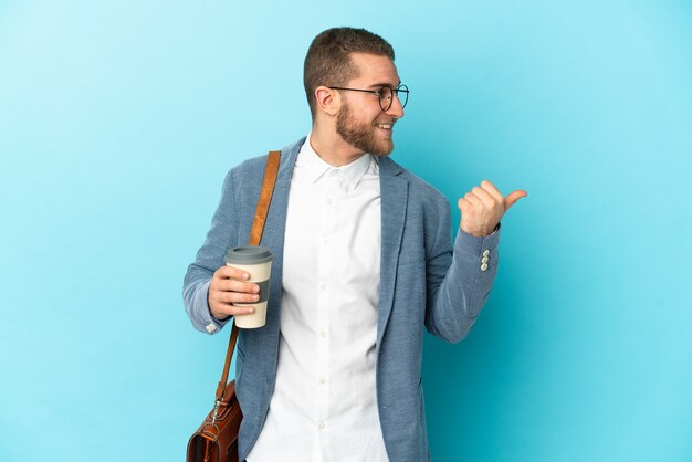 Young caucasian businessman isolated on blue pointing to the side to present a product