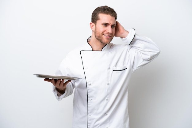 Young caucasian chef with tray isolated on white background having doubts