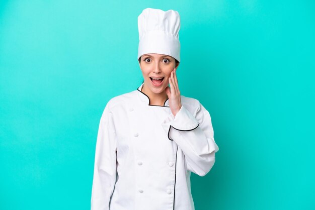 놀라움과 놀란 표정으로 파란색 배경에 고립 된 젊은 백인 요리사 여자