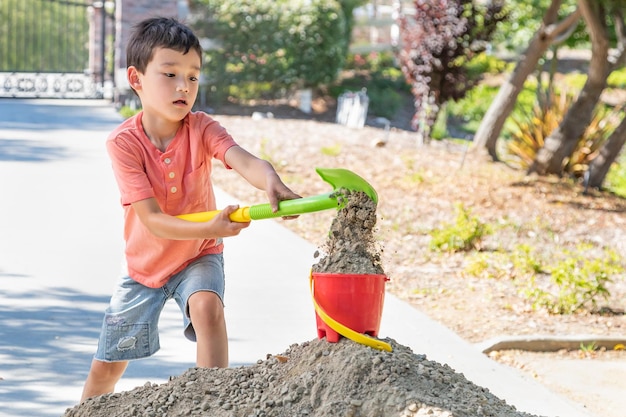 白人 と 中国 人 の 少年 が <unk> と バケツ で 遊ん で いる