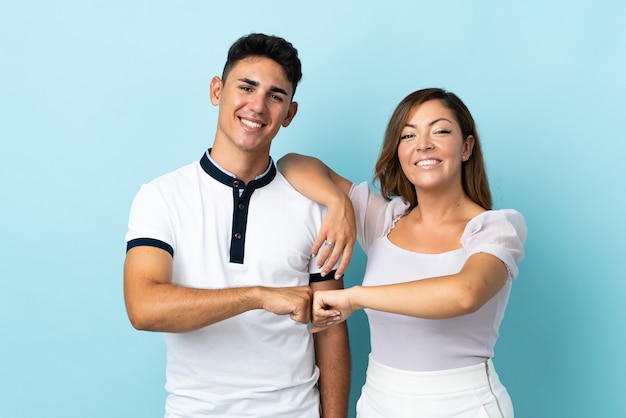 Young caucasian couple on blue bumping fists