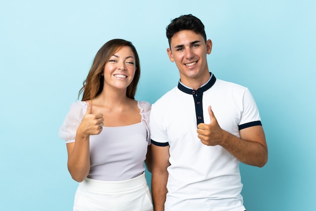 Young caucasian couple on blue giving thumbs up gesture