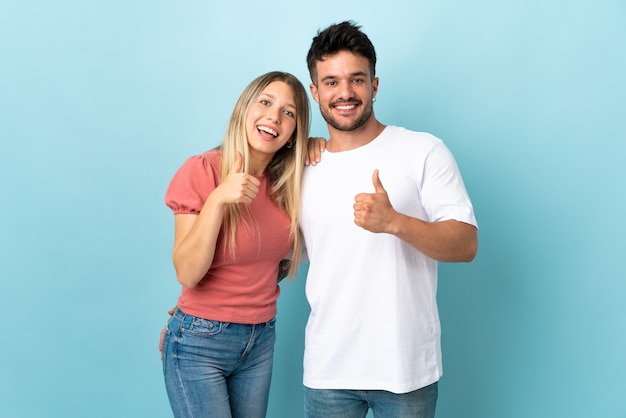 Young caucasian couple on blue giving thumbs up gesture