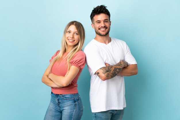 Young caucasian couple on blue keeping arms crossed