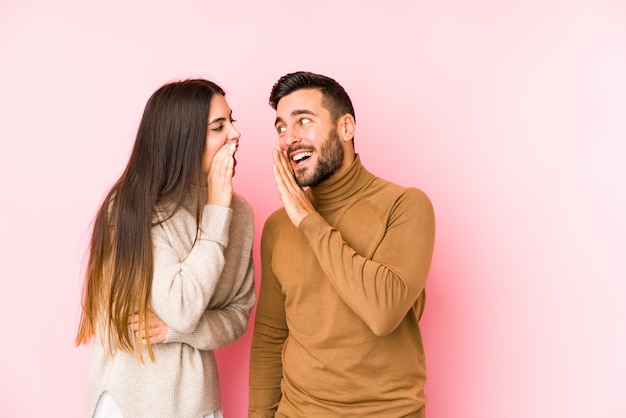 Young caucasian couple isolated is saying a secret hot braking news and looking aside