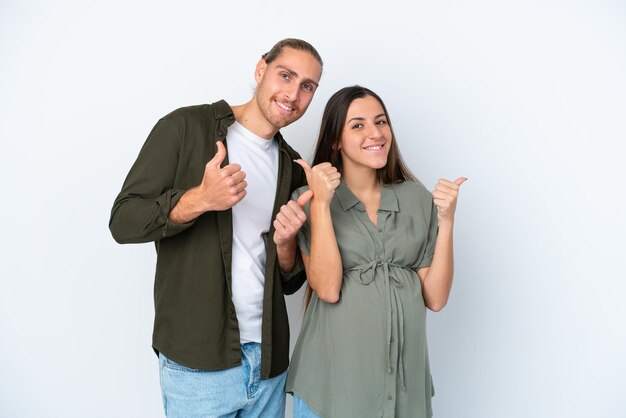 Young caucasian couple isolated on white background pregnant and with thumb up