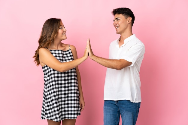 Young caucasian couple on pink bumping hands