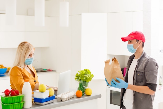 Young Caucasian couple in protective masks doing shoppings at home, quarantine