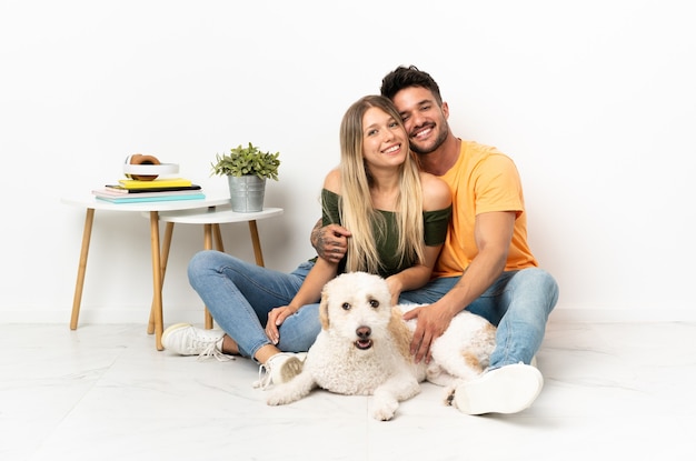 Young caucasian couple with dog staying at home hugging