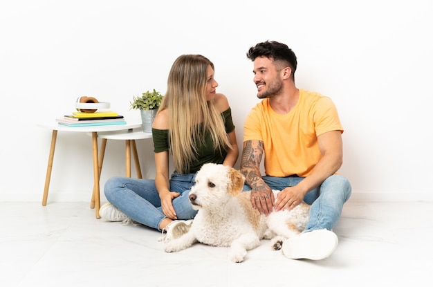 Young caucasian couple with dog staying at home with happy expression