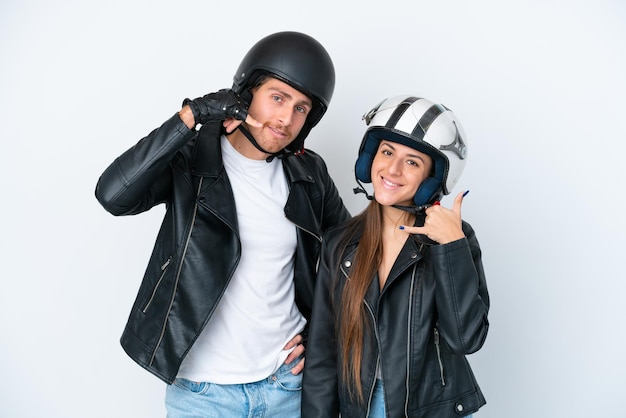 전화 제스처를 만드는 흰색 배경에 고립 오토바이 헬멧을 쓴 젊은 백인 부부 다시 서명