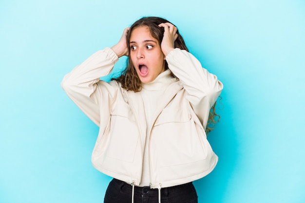 Foto giovane donna caucasica capelli ricci isolata urlando, molto eccitata, appassionata, soddisfatta di qualcosa.