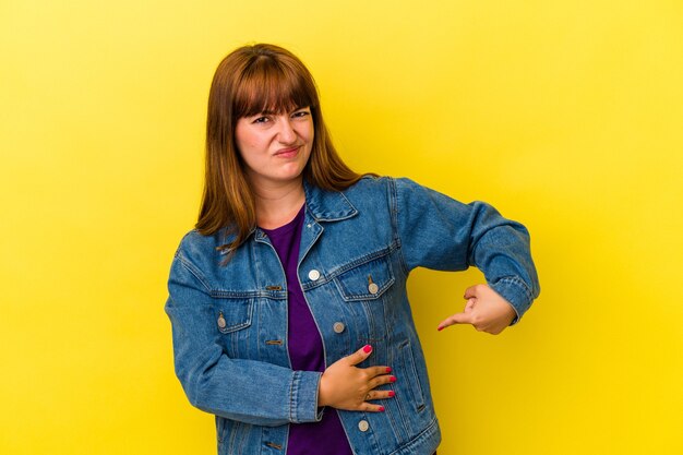 Photo young caucasian curvy woman isolated on yellow background having a liver pain, stomach ache.