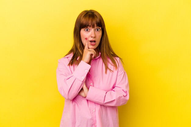 Young caucasian curvy woman isolated on yellow background looking sideways with doubtful and skeptical expression.