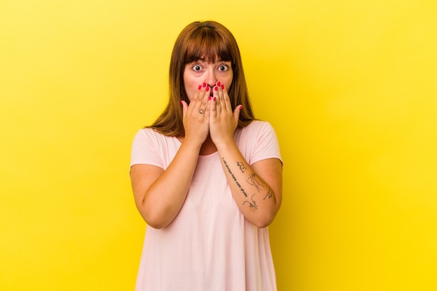 Young caucasian curvy woman isolated on yellow background shocked, covering mouth with hands, anxious to discover something new.