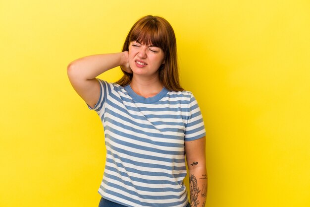 Photo young caucasian curvy woman isolated on yellow background tired and very sleepy keeping hand on head.