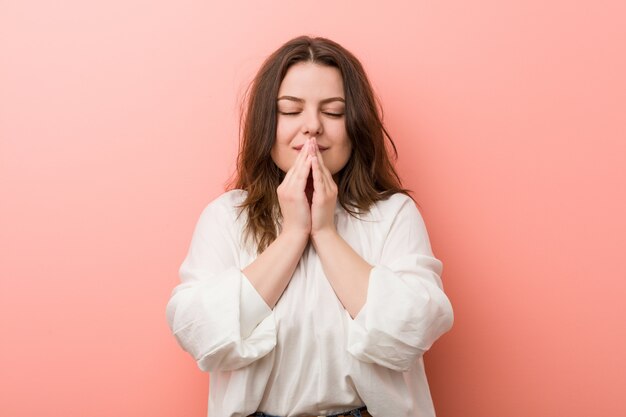 Young caucasian curvy woman standing against pink wall