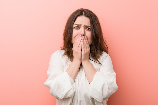 Young caucasian curvy woman standing against pink 