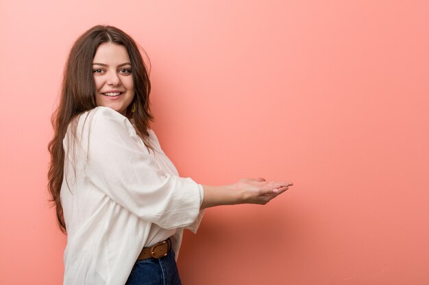 Young caucasian curvy woman standing against pink 