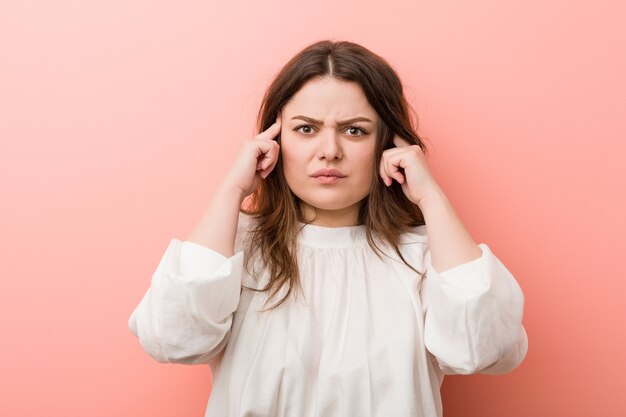 Young caucasian curvy woman standing against pink 