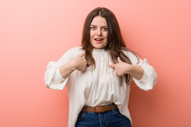 Young caucasian curvy woman standing against pink