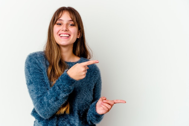 Young caucasian cute woman isolated on white background pointing with forefingers to a copy space, expressing excitement and desire.