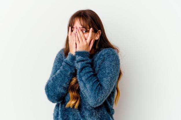 Young caucasian cute woman isolated on white wall blink through fingers frightened and nervous.