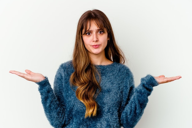 Young caucasian cute woman isolated on white wall doubting and shrugging shoulders in questioning gesture