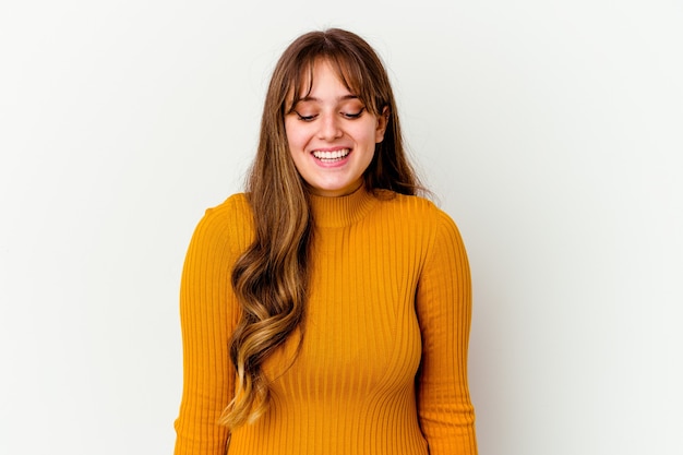 Young caucasian cute woman isolated on white wall laughs and closes eyes, feels relaxed and happy.