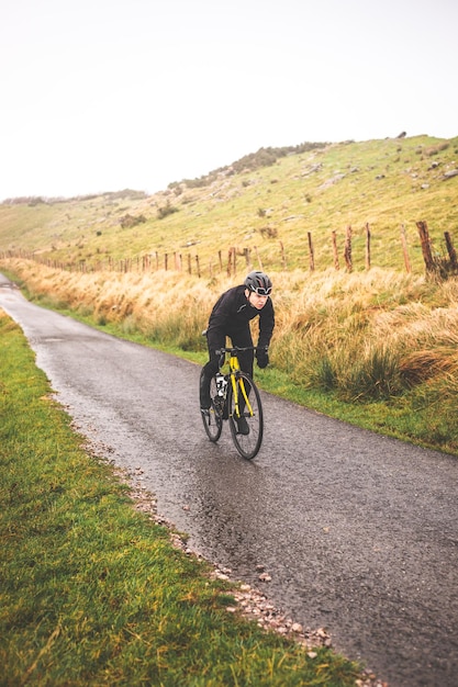 Young caucasian cyclist man climbing a hill in a foggy mountain.