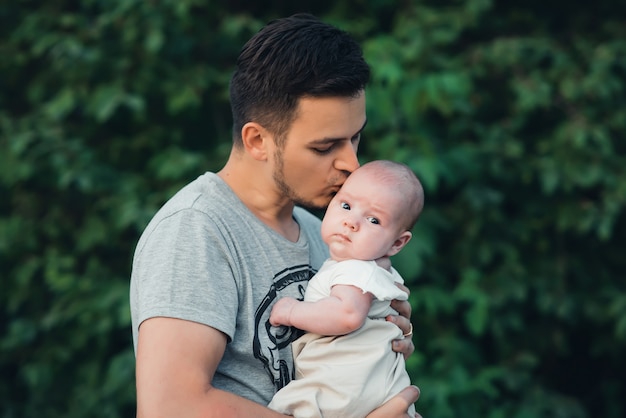 Young Caucasian dad with beard hugs newborn baby boy son