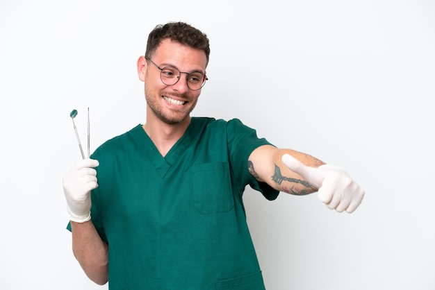 Young caucasian dentist man isolated on white background giving a thumbs up gesture