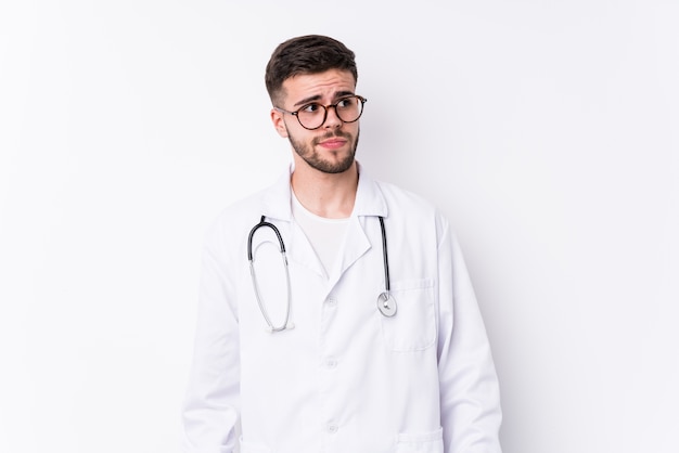 Young caucasian doctor man isolated confused, feels doubtful and unsure.