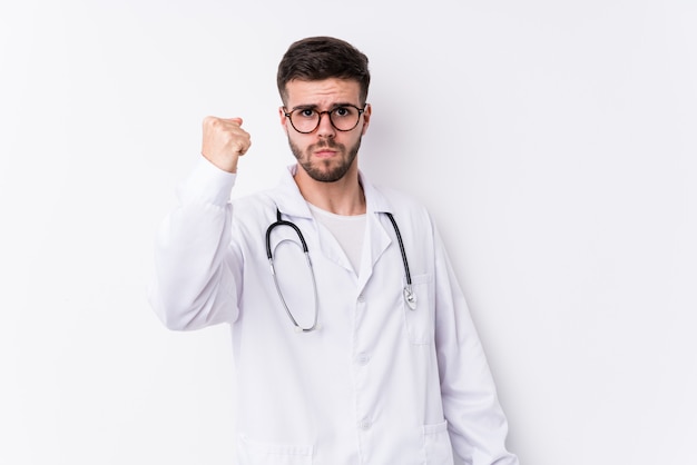 Young caucasian doctor man isolated showing fist to camera, aggressive facial expression.
