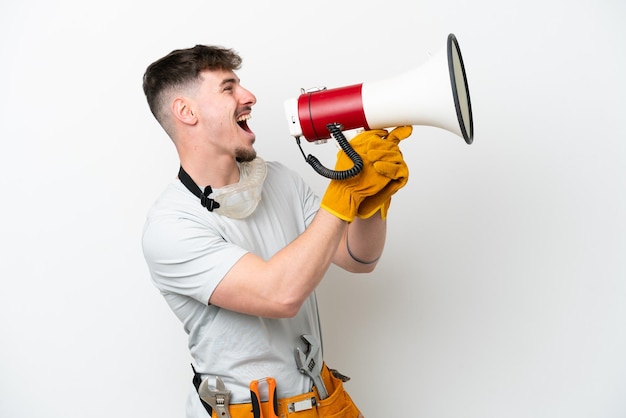 Young caucasian electrician man isolated on white background shouting through a megaphone