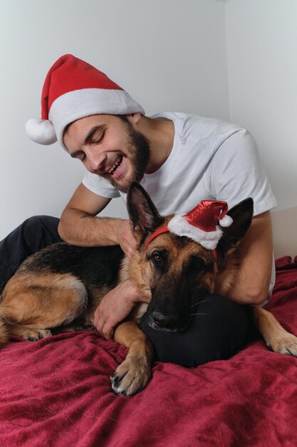 Young Caucasian European man with beard and red Santa hat is sitting on blanket