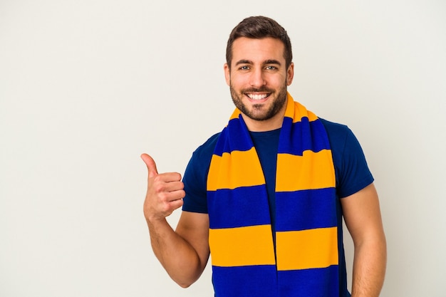 Young caucasian fan of a soccer team isolated on white background smiling and raising thumb up