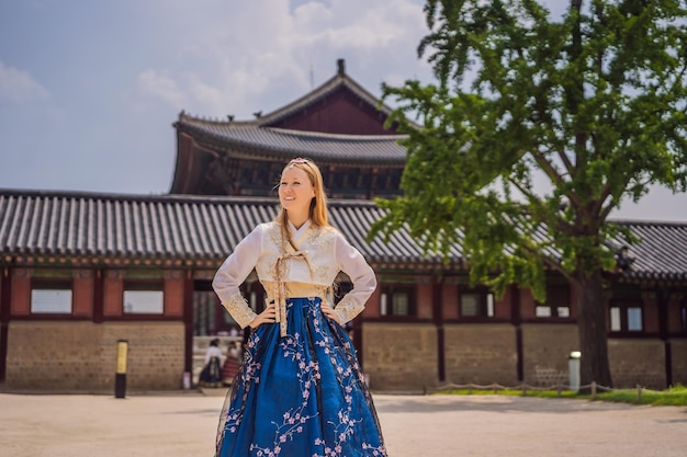 Young caucasian female tourist in hanbok national korean dress at Gyeongbokgung Palace Travel to Korea concept National Korean clothing Entertainment for tourists trying on national Korean clothing