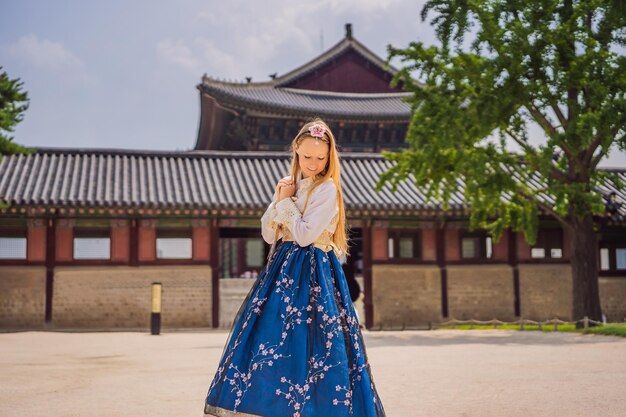 Photo young caucasian female tourist in hanbok national korean dress at gyeongbokgung palace travel to korea concept national korean clothing entertainment for tourists trying on national korean clothing