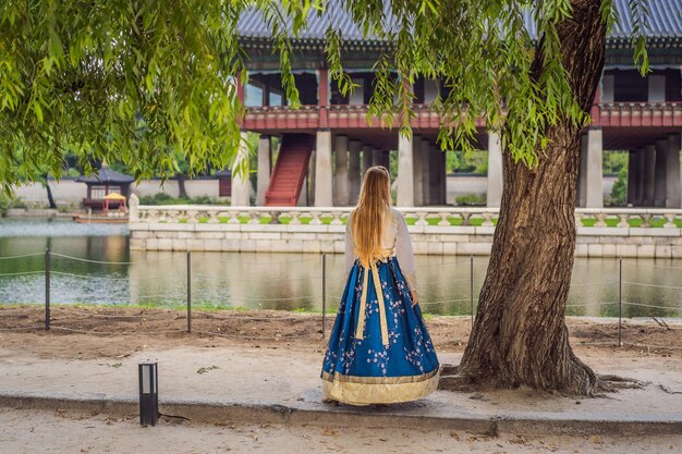 Young caucasian female tourist in hanbok national korean dress at Korean palace Travel to Korea concept National Korean clothing Entertainment for tourists trying on national Korean clothing